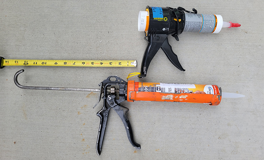 common caulking gun with plunger fully extended and laid out next to a ruler