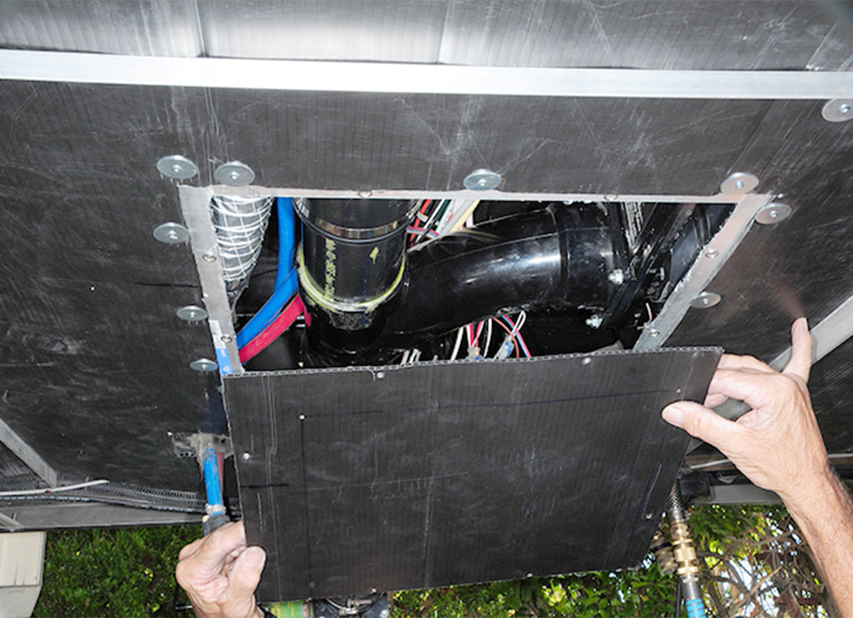 access panel being removed from the underside of an RV