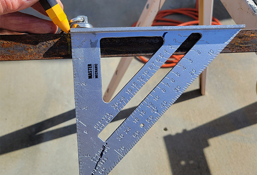 speed square ruler being used to draw a straight line on an iron rod
