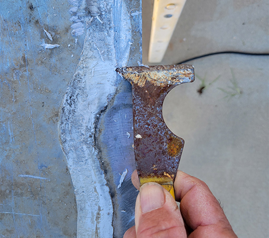 closeup of a putty knife scraping old caulking from the diamond plate