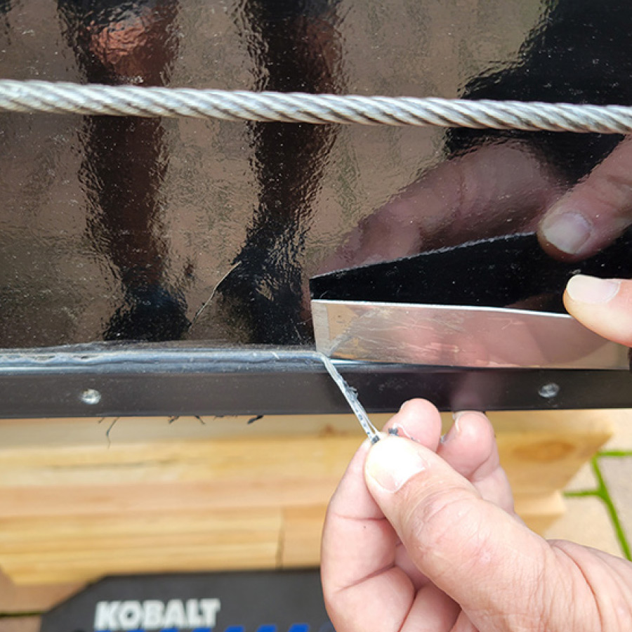a putty knife lifting the sealant away from the molding