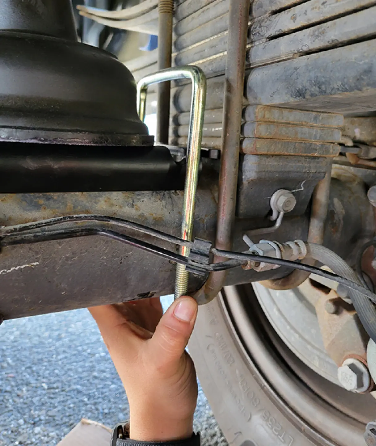 a U-bolt positioned over the bottom bracket and axle housing