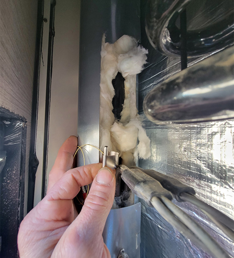 hand moving the bracket and temperature sensor onto the boiler tube