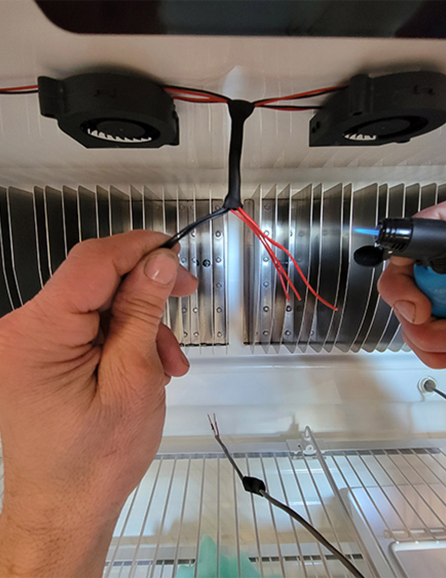 closeup of person soldering fan wires into shrink tubing