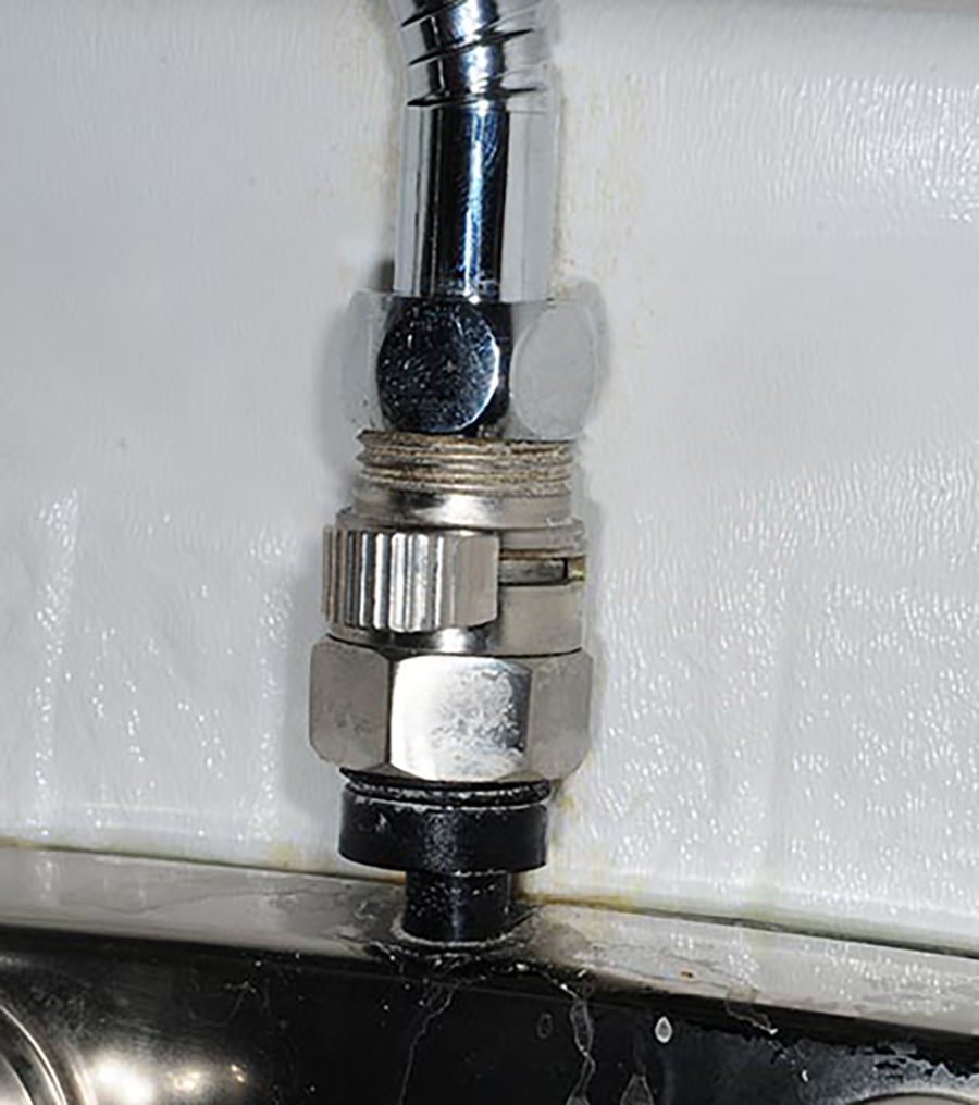 Close-up portrait photograph view of the optional Shut-Off Valve of the showerhead, which has an ergonomically placed button that works smoothly at first, but I found that over time the button becomes more difficult to push; Still, the ability to cut water flow while soaping up in the shower is paramount to most RVers; our choice is the KES Shut Off Brass Shower Head Valve (K1140B-2) available from Amazon. It’s mounted to the shower diverter faucet and has been working smoothly for years.