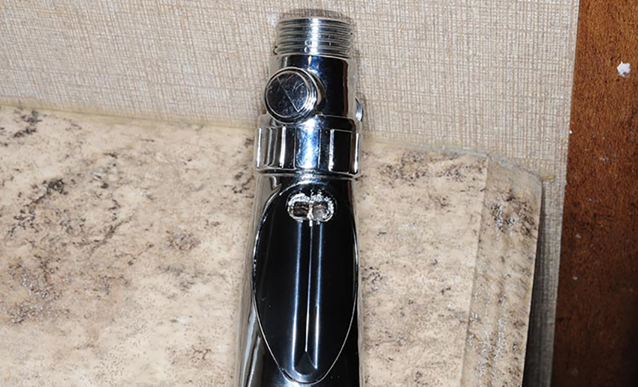 Close-up portrait photograph view of the holes in the handle of the Jetstorm showerhead, which allow air to enter and mix with the water to provide a strong, water-saving stream of water