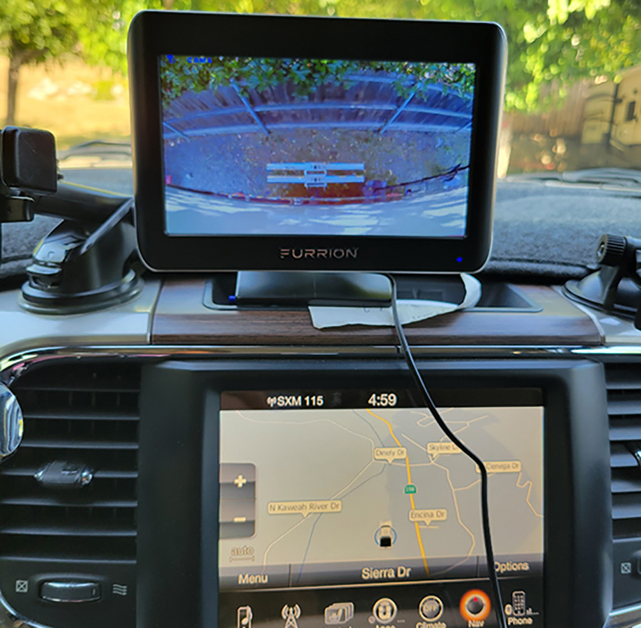 Portrait inside close-up photograph view of the 7-inch monitor Furrion Vision S Wireless RV Backup Camera System device located temporarily set on the dash space area of the vehicle using the specialty bracket that comes with the kit; Other options require the use of the bracket with the suction cup.