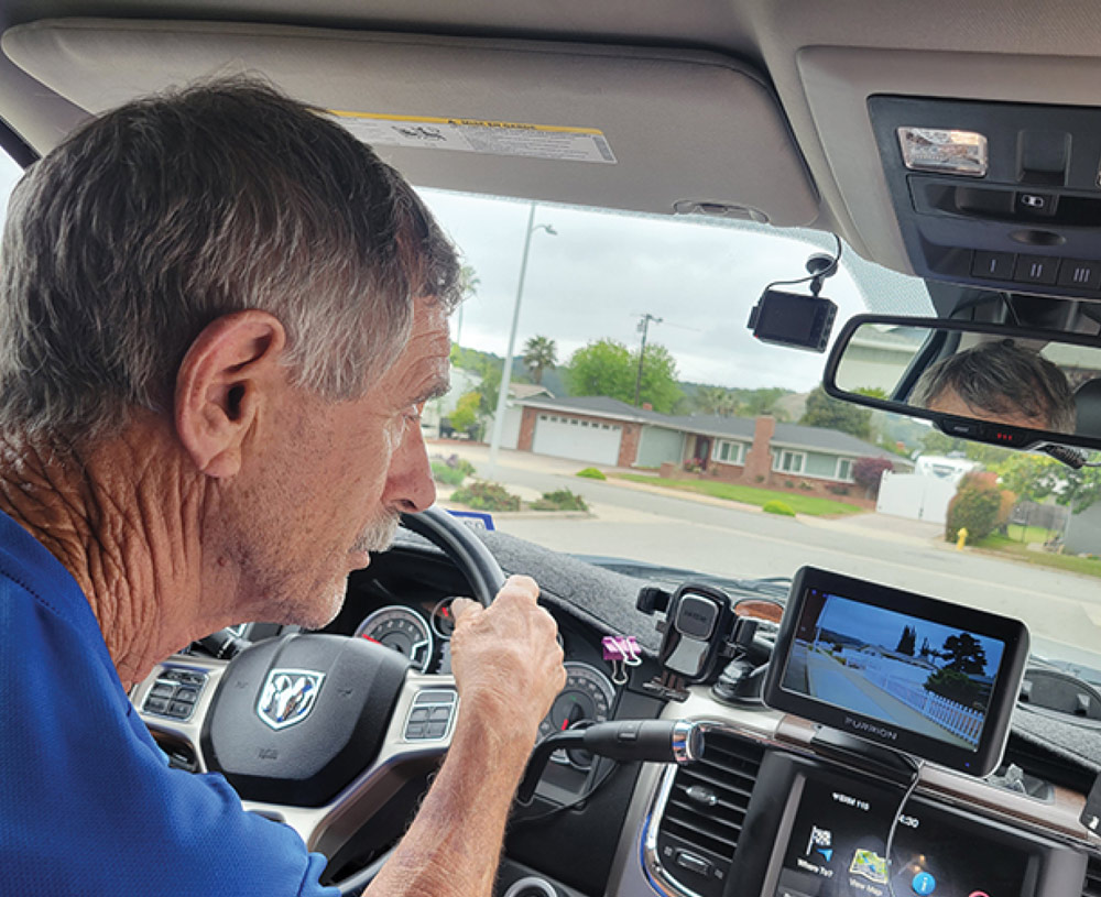 man driving and looking at a back up camera view