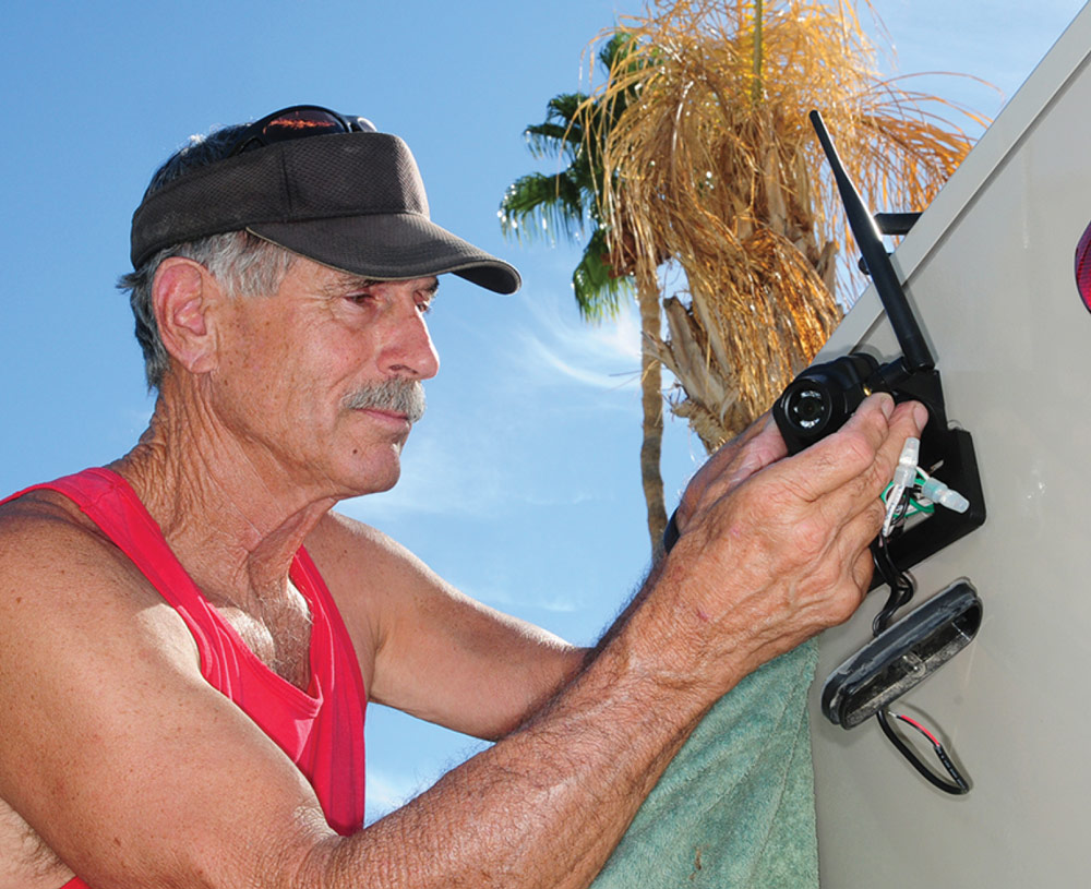 man attaching a back up camera to an RV