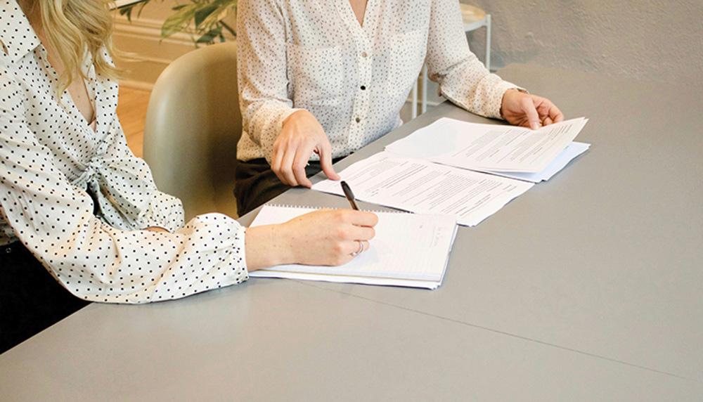 two people looking at and signing paperwork