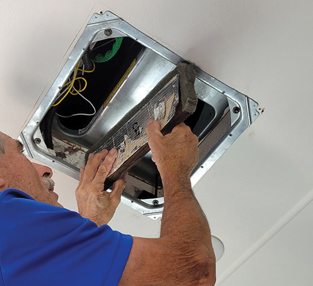 man working on an A/C system in an RV